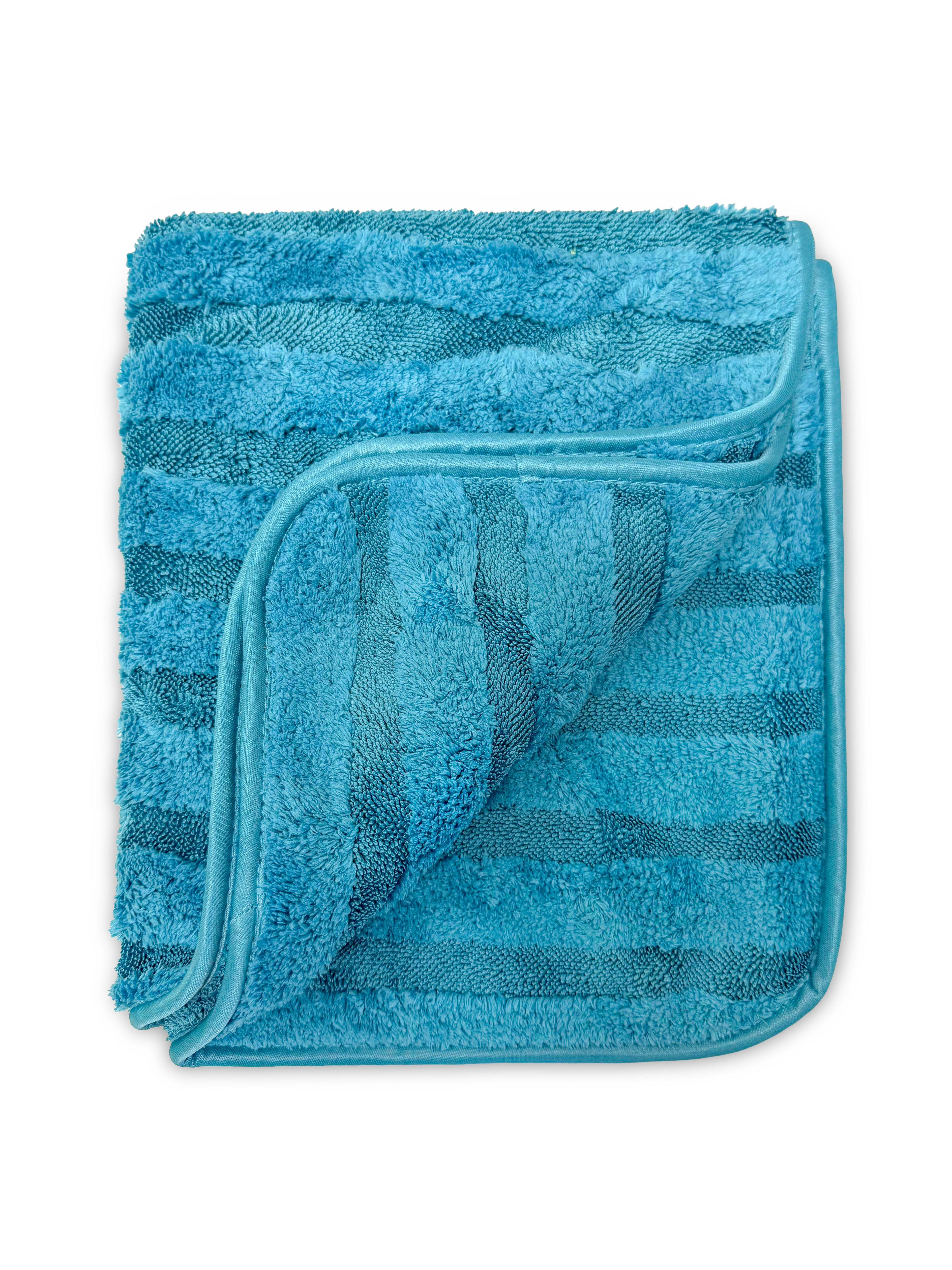 A folded blue terry cloth towel with a plush, textured surface and a slightly lighter blue piping border, shown on a plain white background.